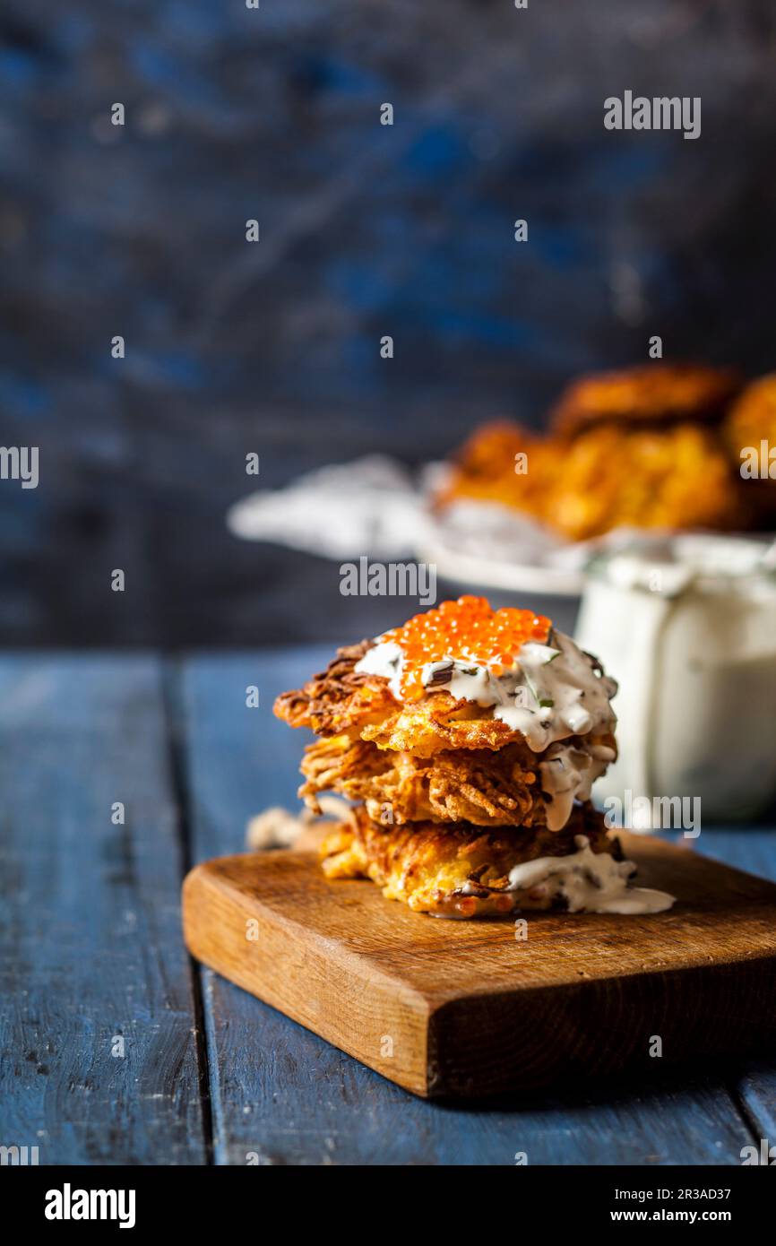 Latkes con porri fritti, panna acida e caviale di trote rosse Foto Stock
