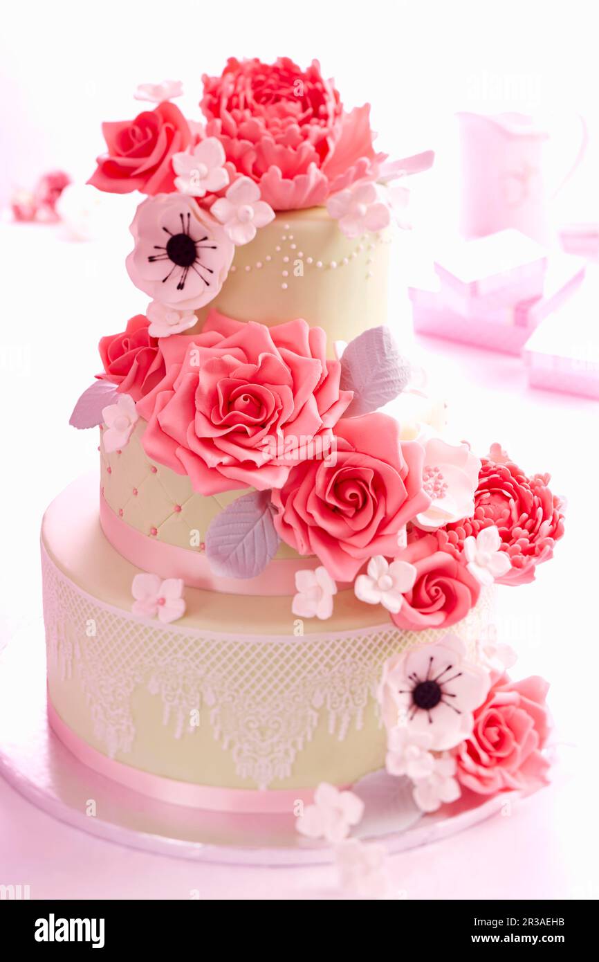 Una torta nuziale con rose e fiori di zucchero Foto Stock