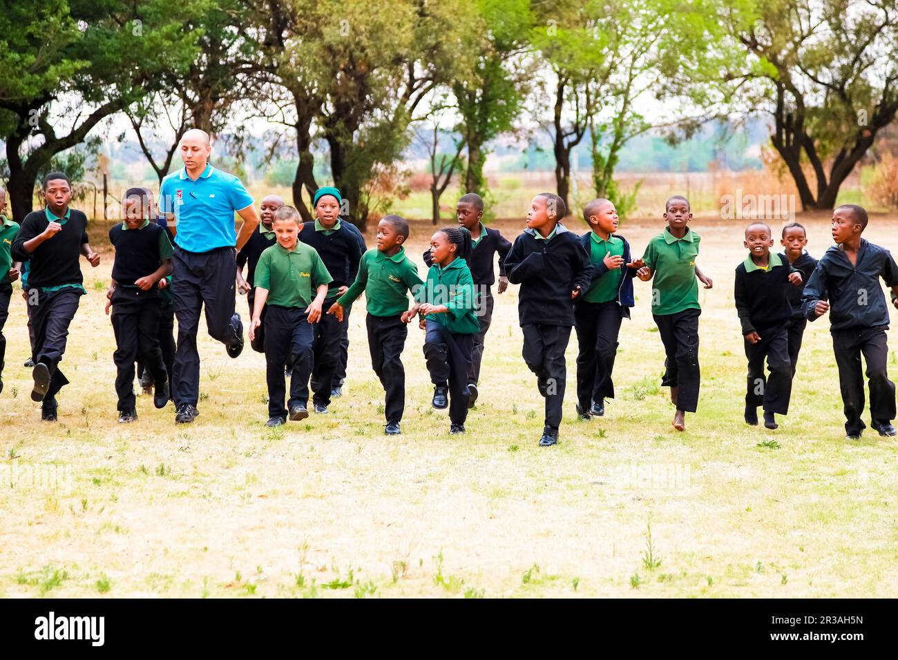 Diversi bambini della scuola primaria africana che fanno esercizio fisico PT lezione Foto Stock