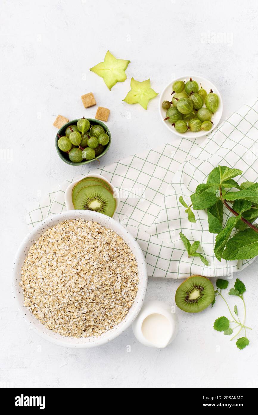 Composizione alimentare con avena, kiwi, uva spina e menta Foto Stock