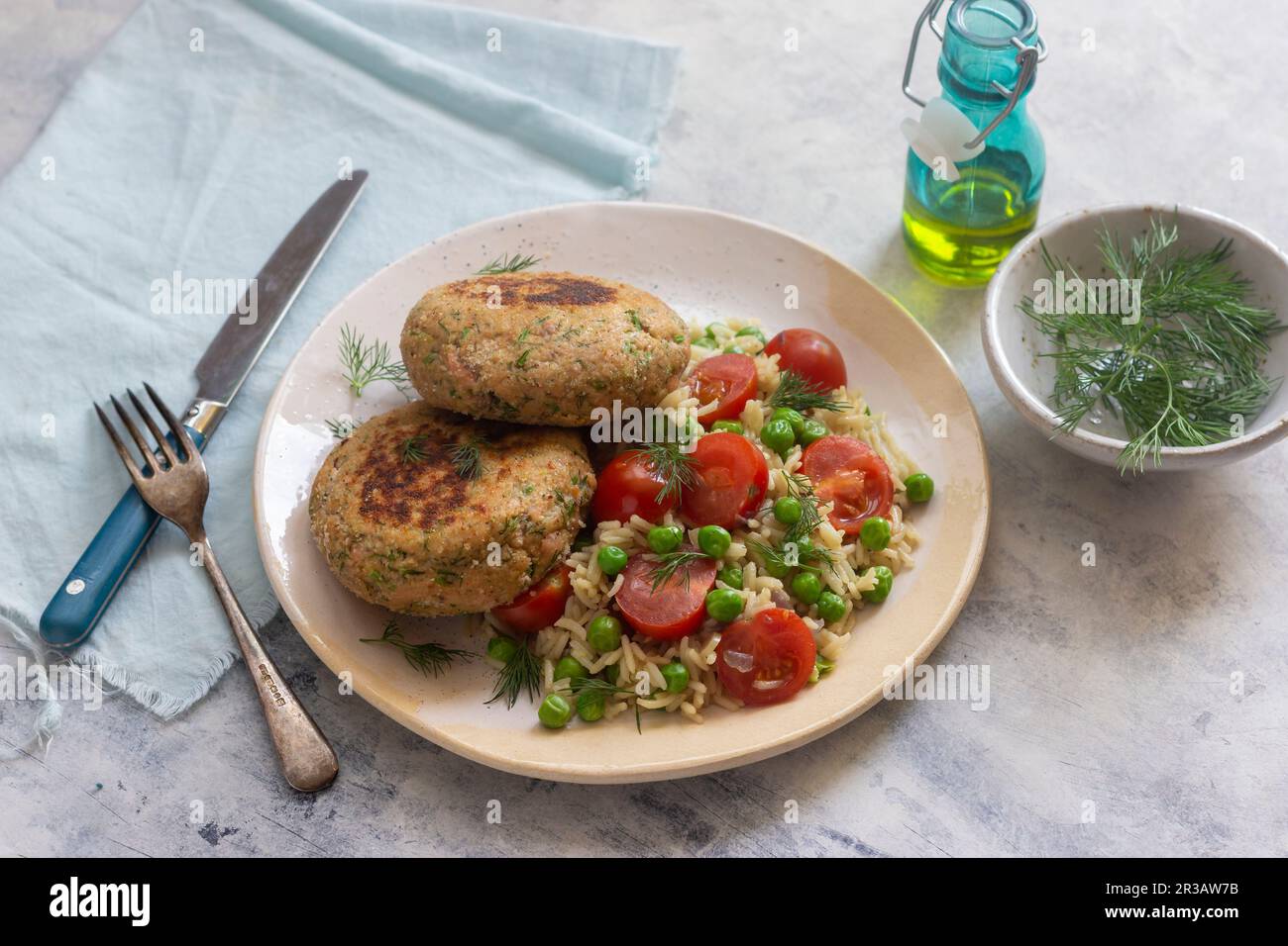 Frittelle di salmone con piselli e risotto al pomodoro, aneto fresco, olio d'oliva Foto Stock