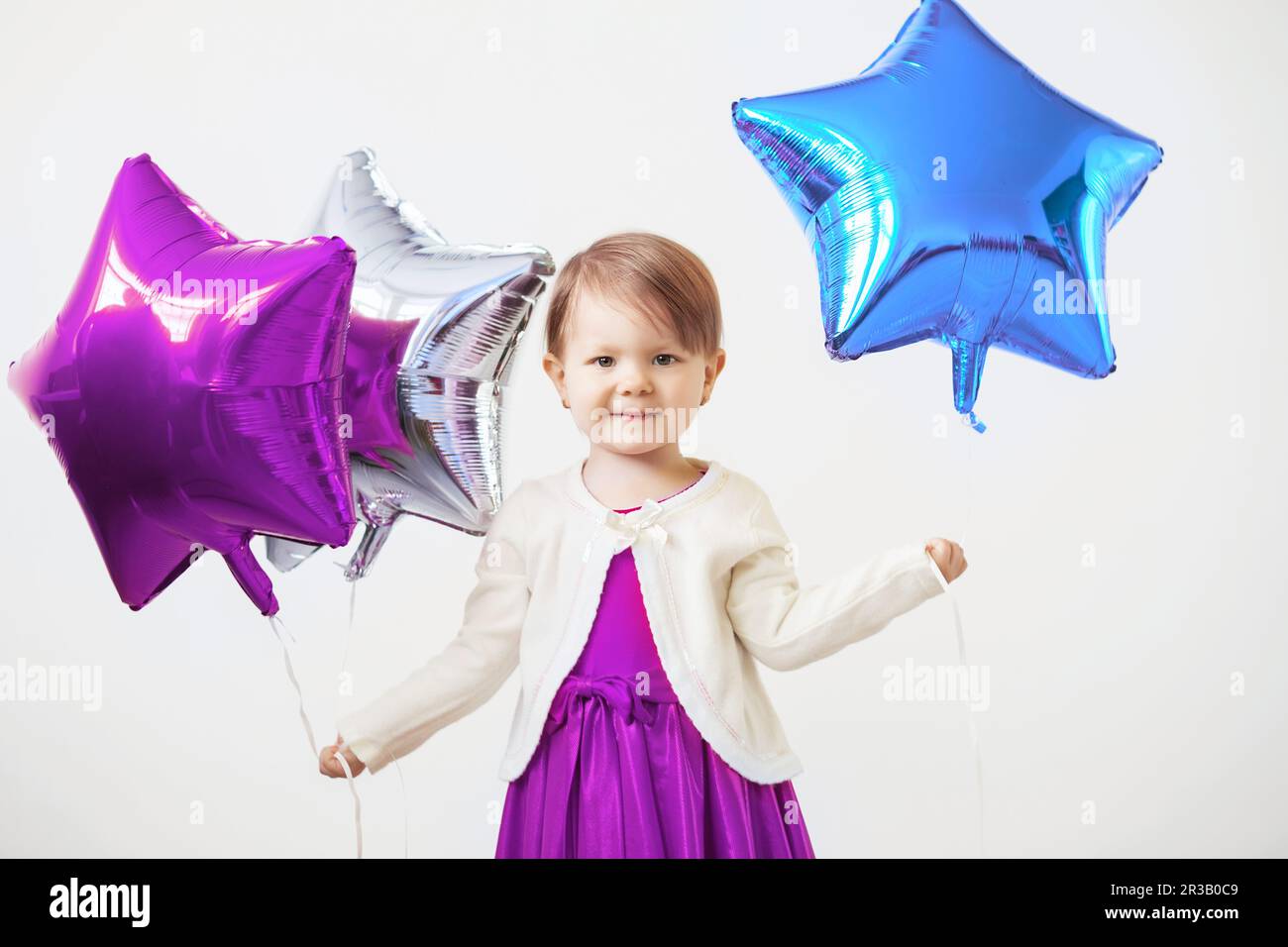 Bambina che tiene palloncini sotto forma di stelle. Ragazza giovane che tiene un palloncino a forma di stella. H Foto Stock