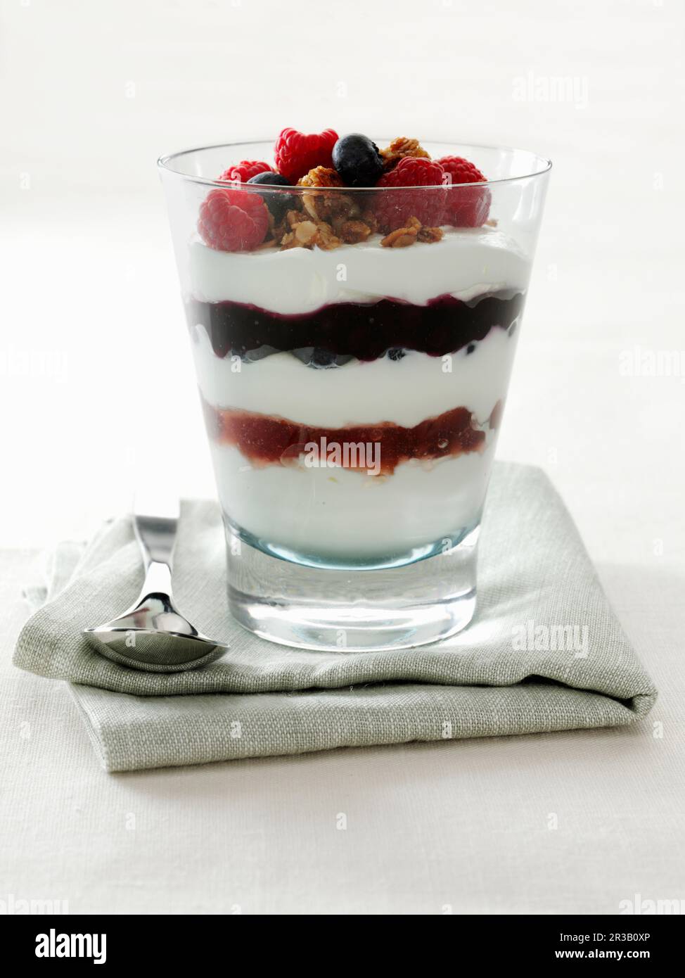 Yogurt Parfait con lamponi e mirtilli guarniti con noci pecan candite Foto Stock