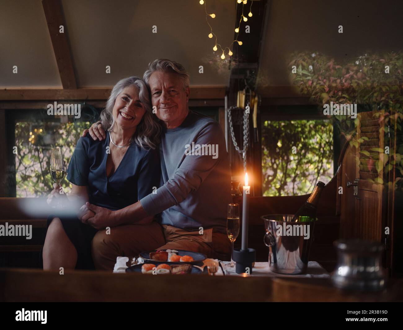 Ritratto di coppia senior avente una cena a lume di candela su una barca in boathouse Foto Stock