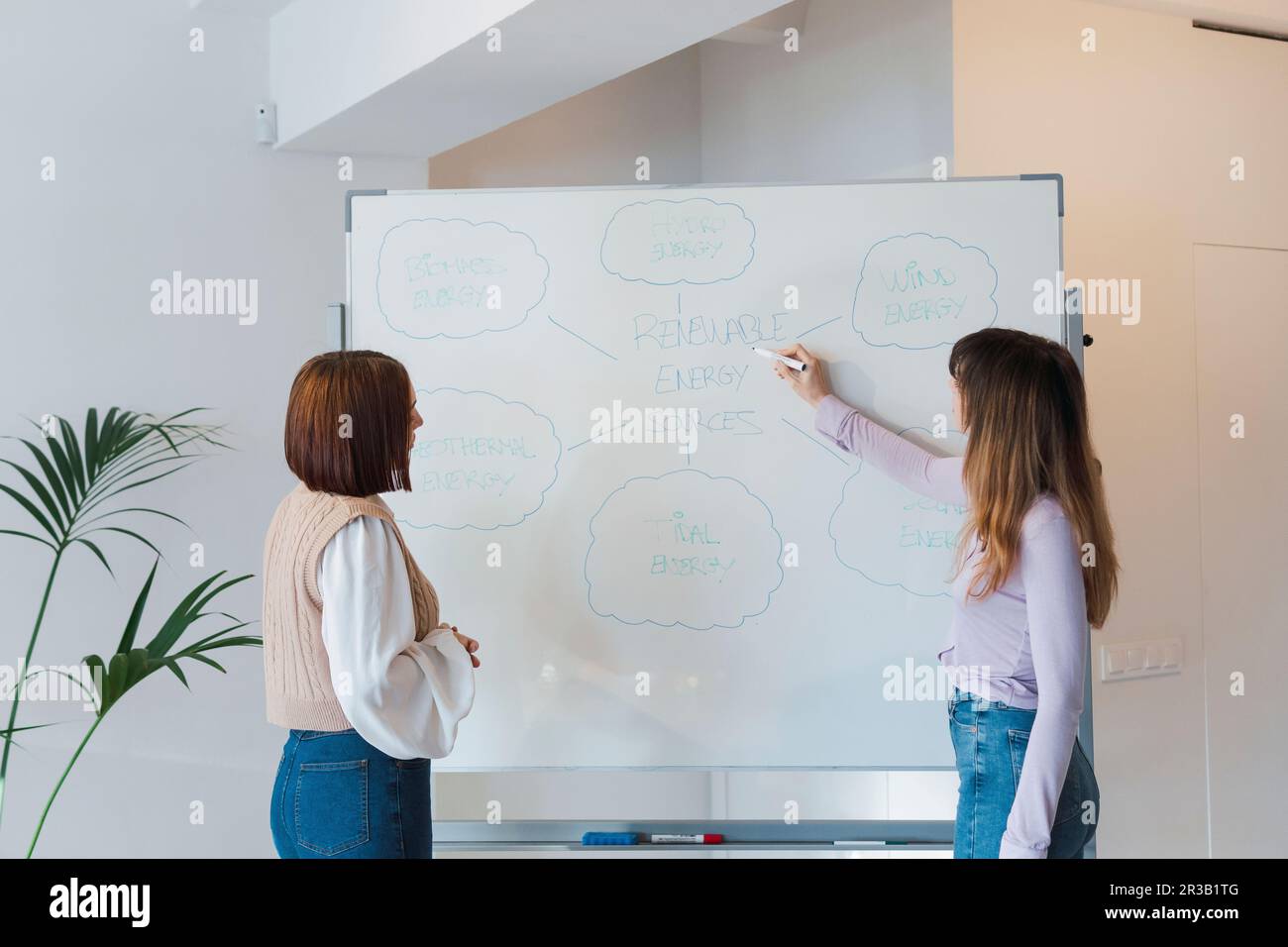 Donna d'affari con un collega che discute sulla lavagna in ufficio Foto Stock