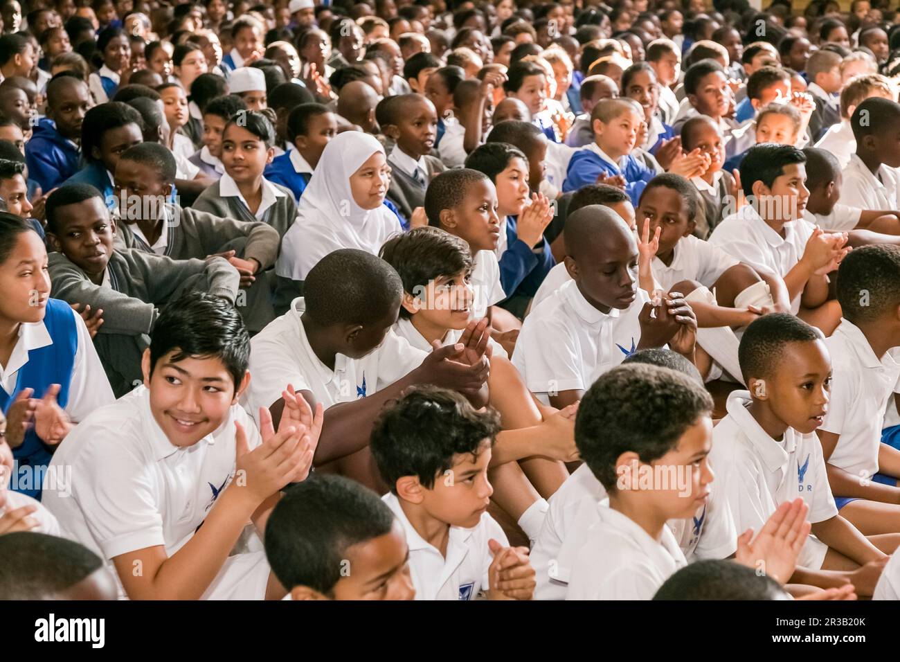 Giovani bambini di scuola diversi seduti sul pavimento in un'assemblea mattutina Foto Stock