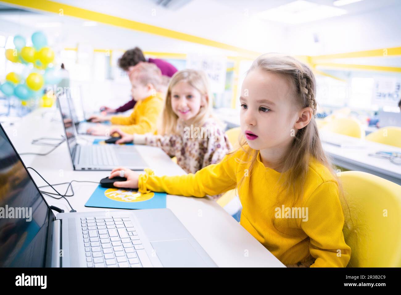 Ragazza che usa un computer portatile seduto in classe computer Foto Stock