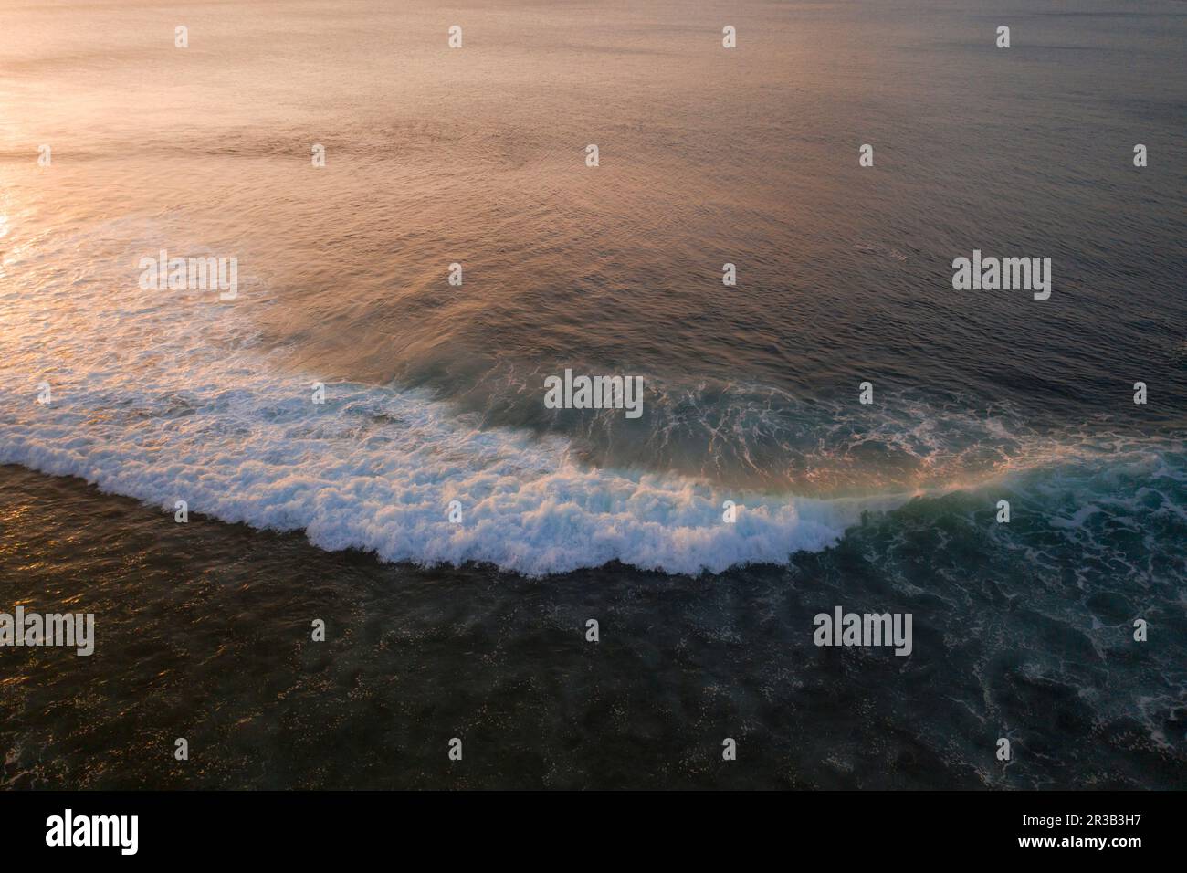 Onde spruzzi d'acqua in mare al tramonto Foto Stock