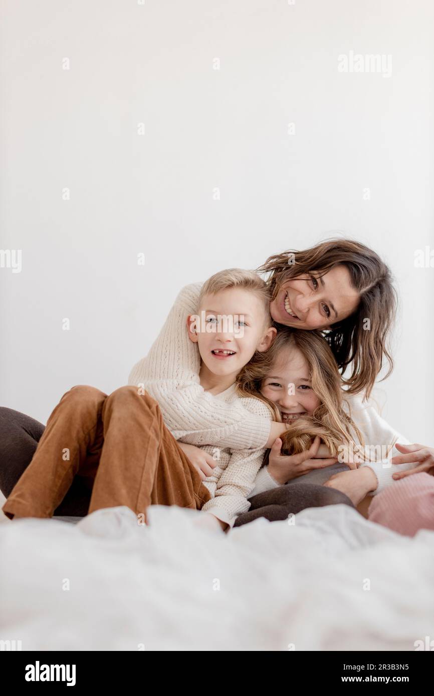 Donna sorridente con figlio e figlia davanti al muro Foto Stock