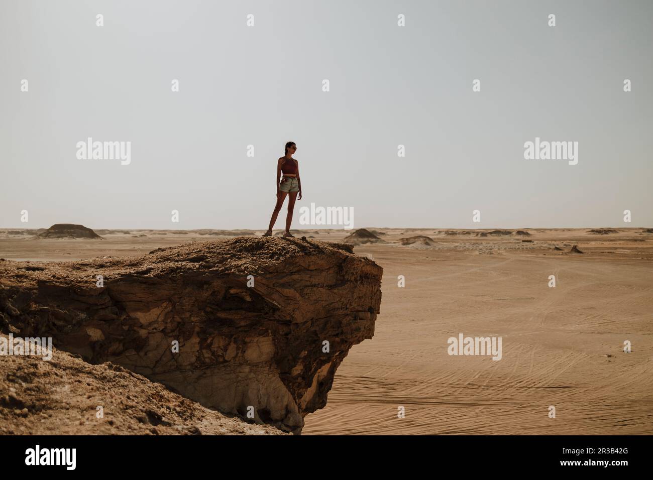 Donna in piedi sulla roccia nel deserto Foto Stock