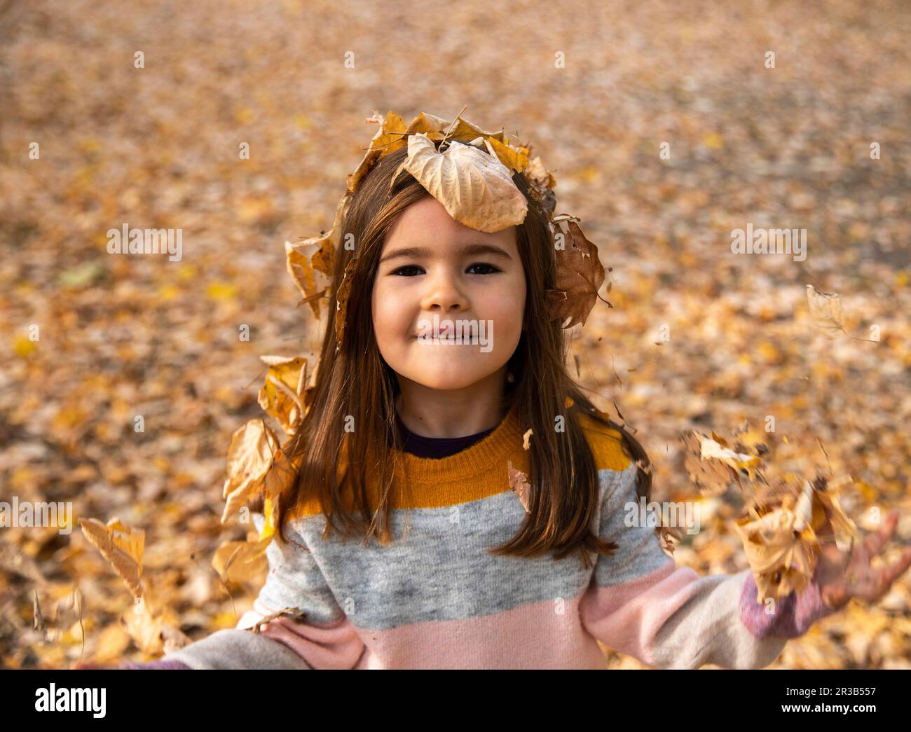 Ragazza sorridente coperta di foglie secche al parco autunnale Foto Stock
