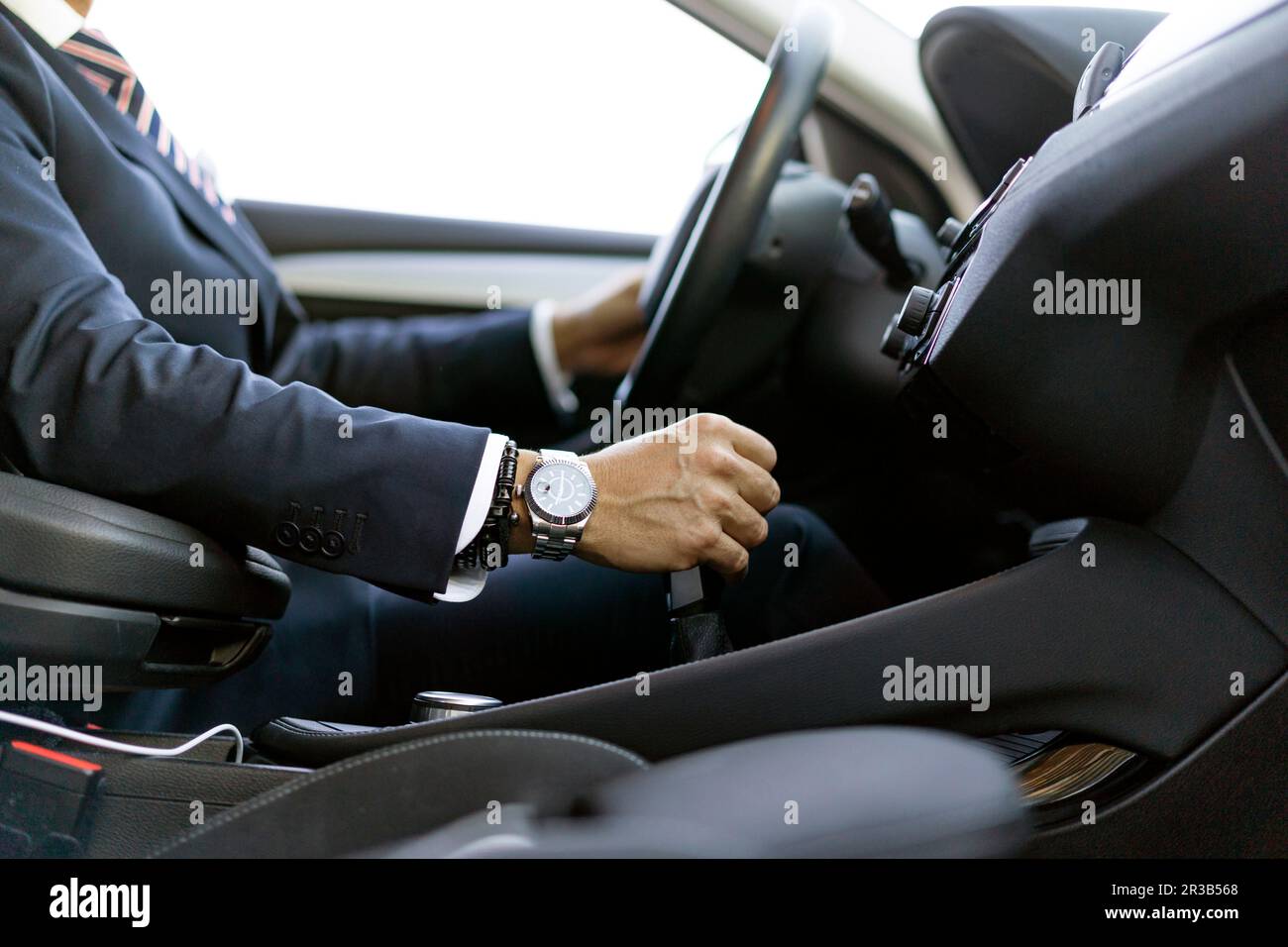 Uomo d'affari che cambia marcia seduto in auto Foto Stock