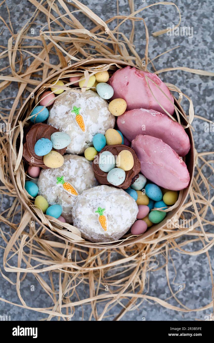 Biscotti di Pasqua con decorazioni rosa e carote, cupcake al cioccolato e mini uova al cioccolato Foto Stock