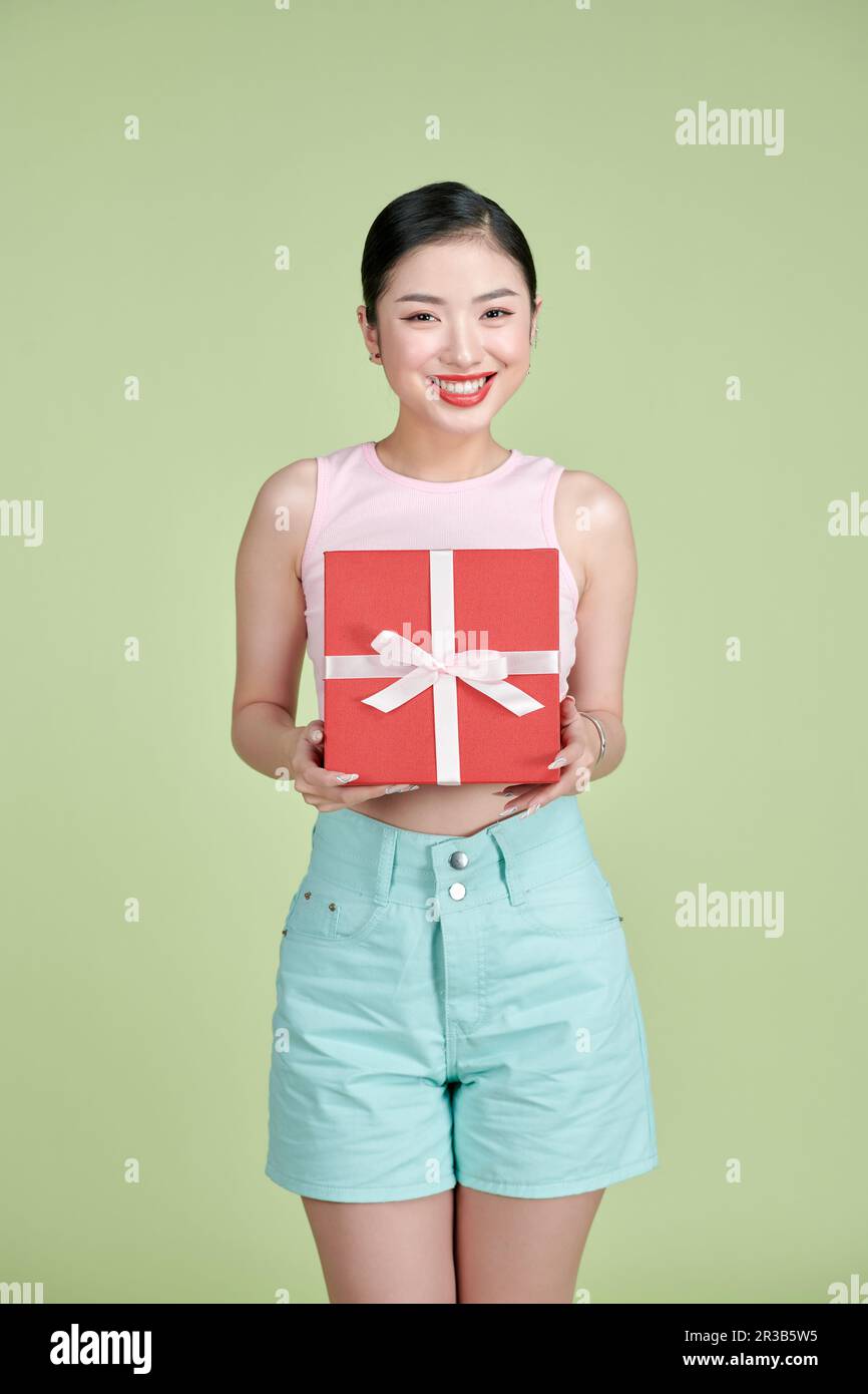 Felice giovane donna che tiene la scatola del regalo sopra lo sfondo verde Foto Stock