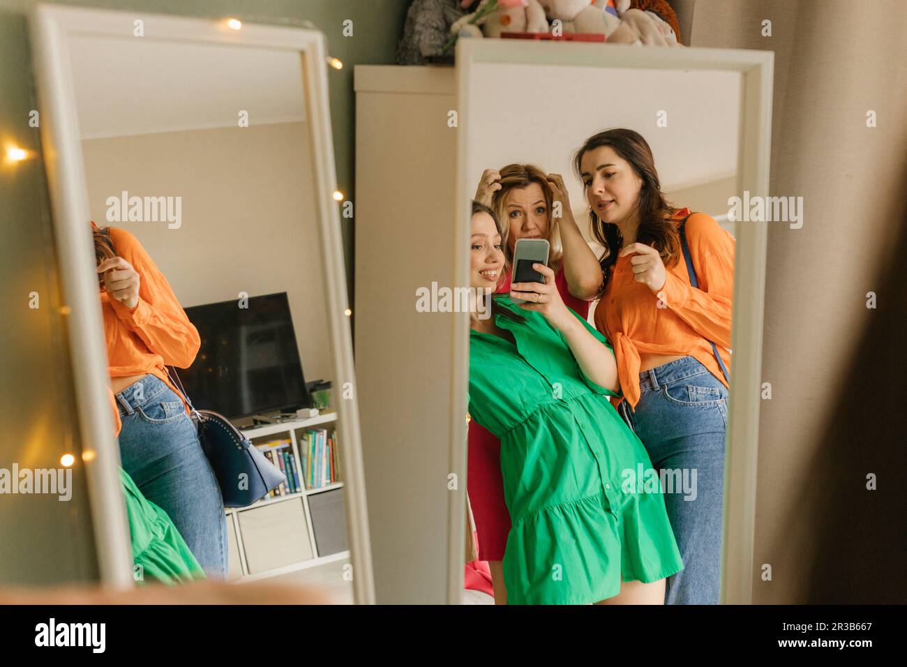Donna che prende selfie specchio con gli amici che vanno per la festa a casa Foto Stock