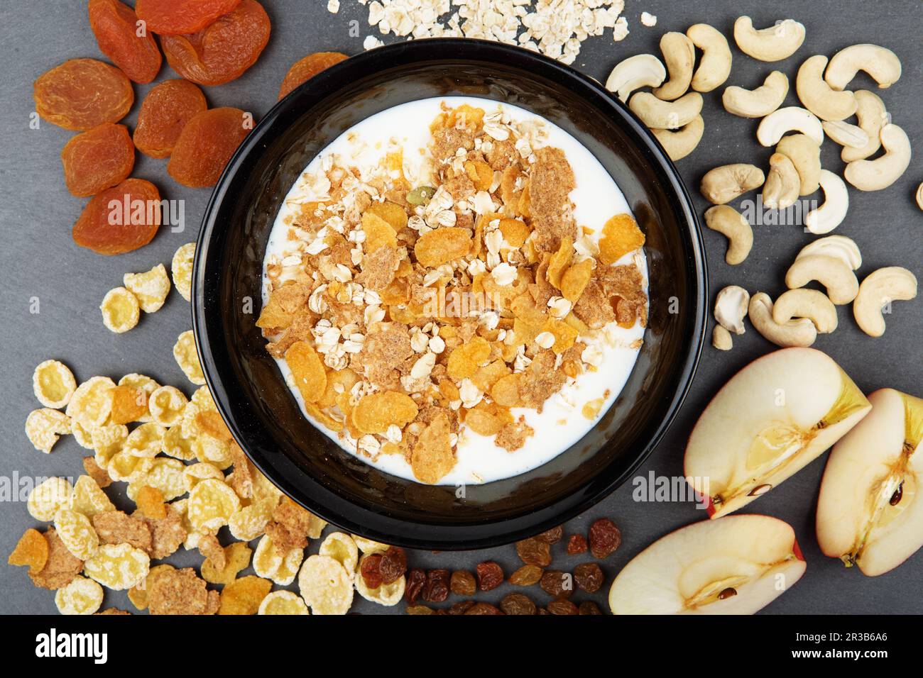 Muesli, noci, frutta, latte e farinata d'avena per colazione. Piatto di fiocchi di avena, anacardi, mele e semi Foto Stock