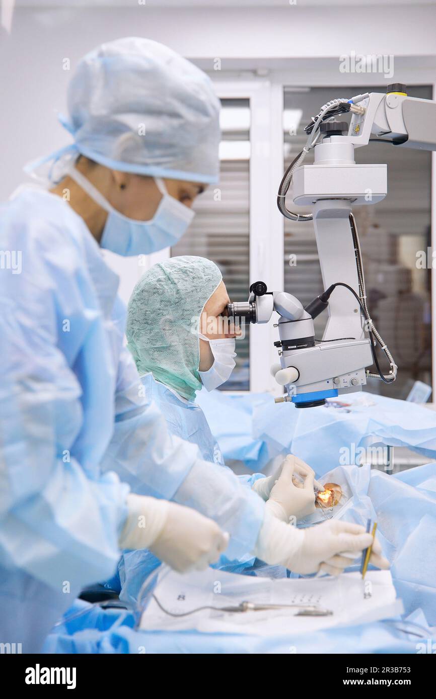 Infermiere con medico che esegue chirurgia oculare in sala operatoria Foto Stock