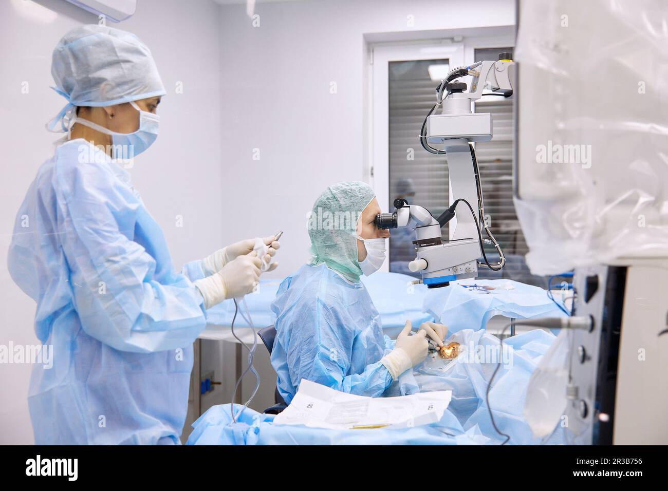 Infermiere con chirurgo che esegue chirurgia oculare in sala operatoria Foto Stock