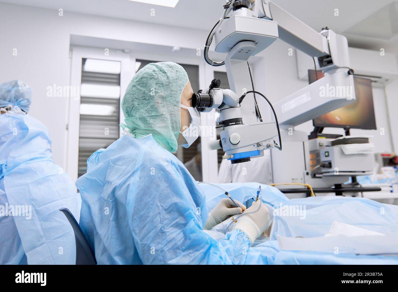Chirurgo che esegue la chirurgia oculare utilizzando il microscopio in sala operatoria Foto Stock
