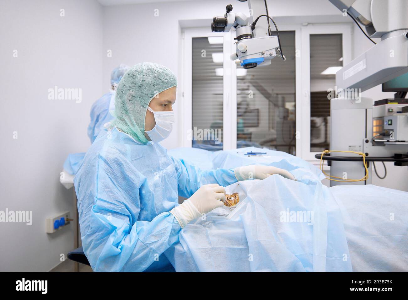 Chirurgo che esamina l'occhio del paziente in sala operatoria Foto Stock