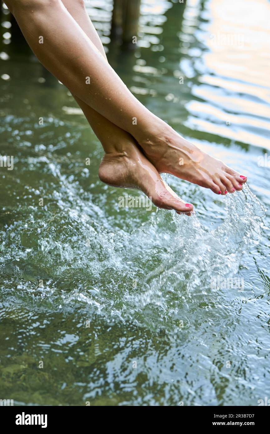 Donna spruzzi d'acqua con i piedi nel lago Foto Stock