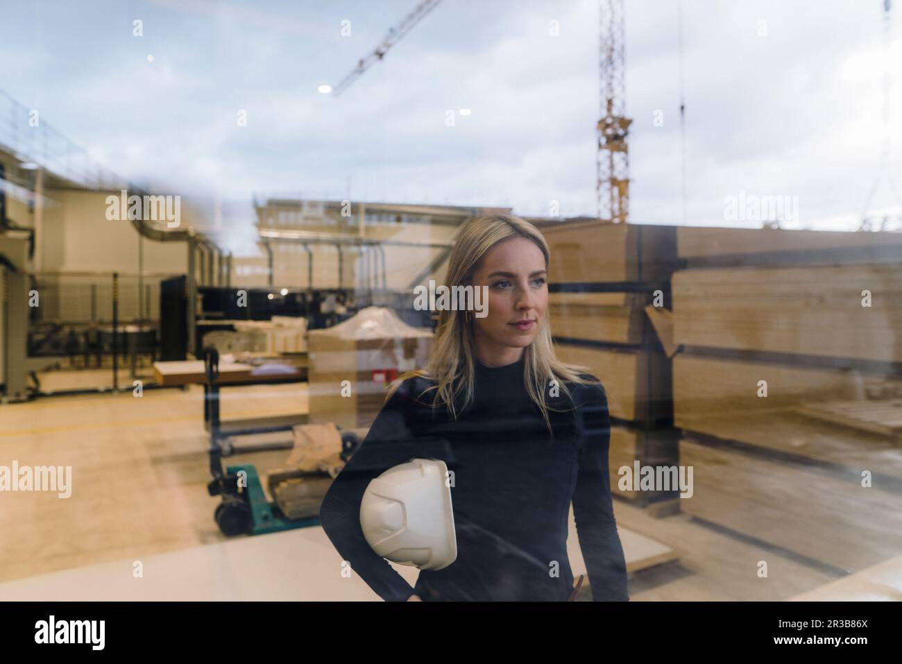 Donna d'affari in piedi in fabbrica visto attraverso il vetro Foto Stock