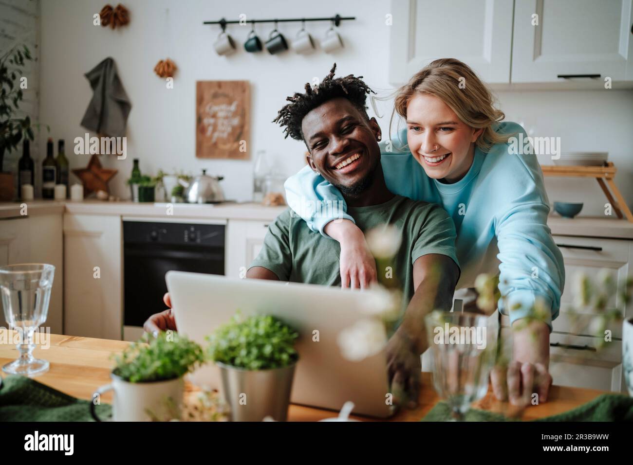 Giovane coppia che guarda il computer portatile in cucina a casa Foto Stock