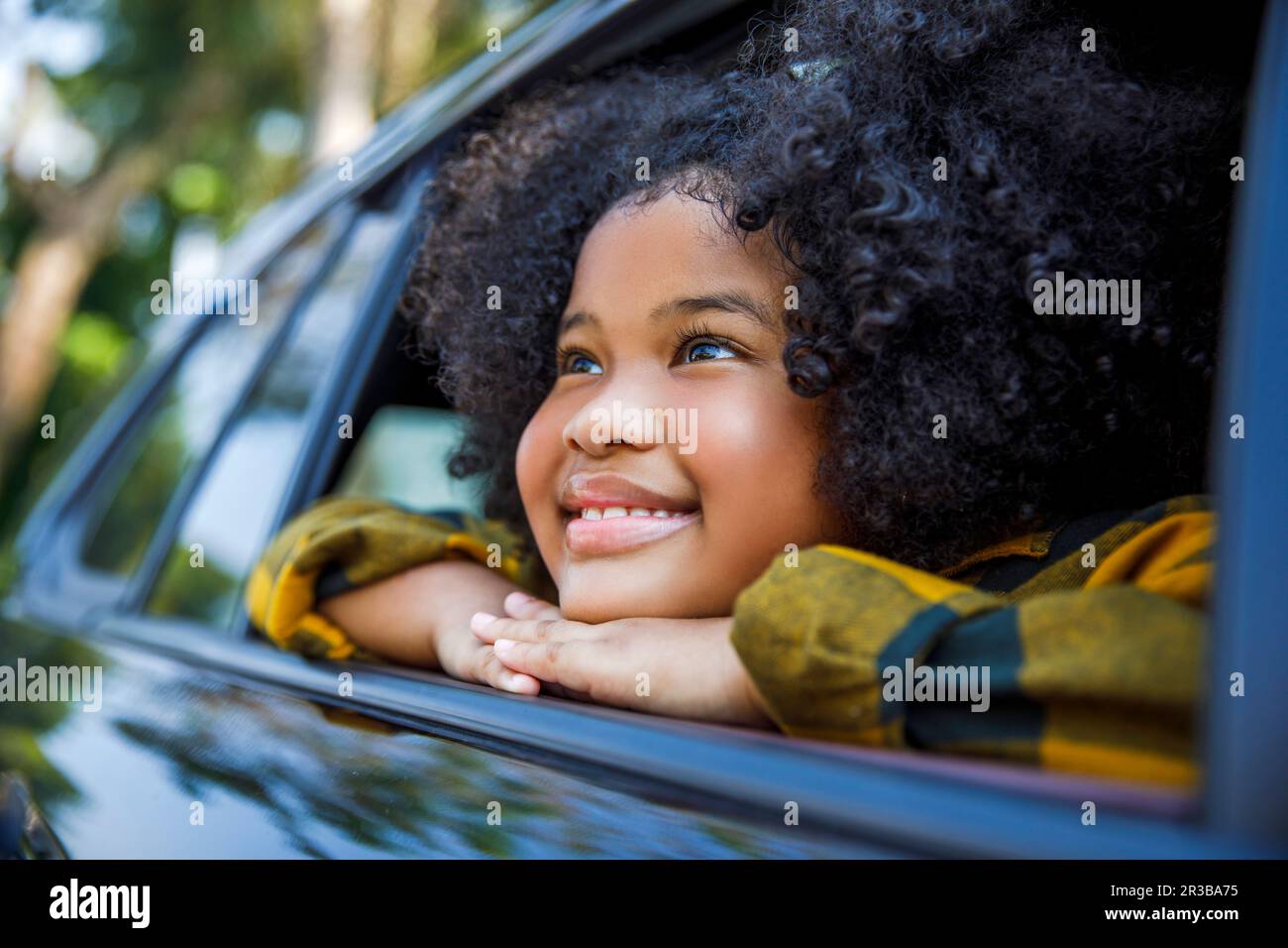 Sorridente ragazza giorno sognando e appoggiandosi sul finestrino dell'automobile Foto Stock