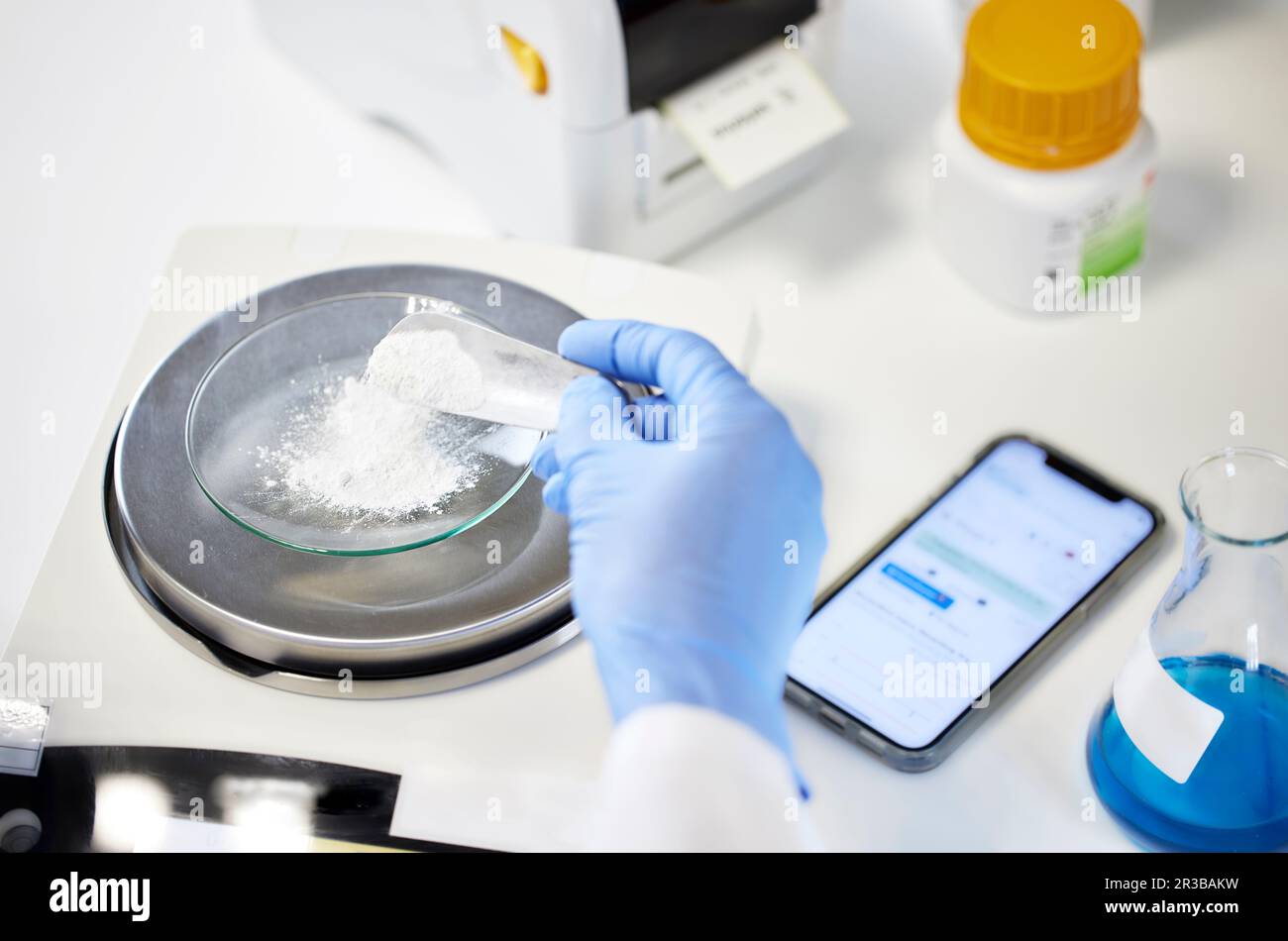 Mano dello scienziato che misura la sostanza chimica sulla bilancia in laboratorio Foto Stock