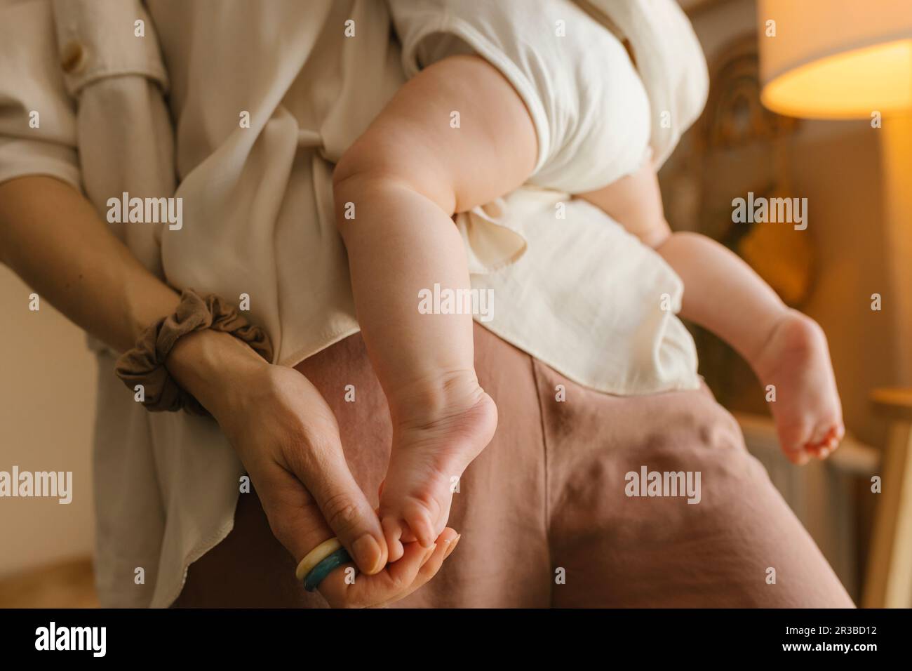 Madre che trasporta e tocca il piede della bambina Foto Stock