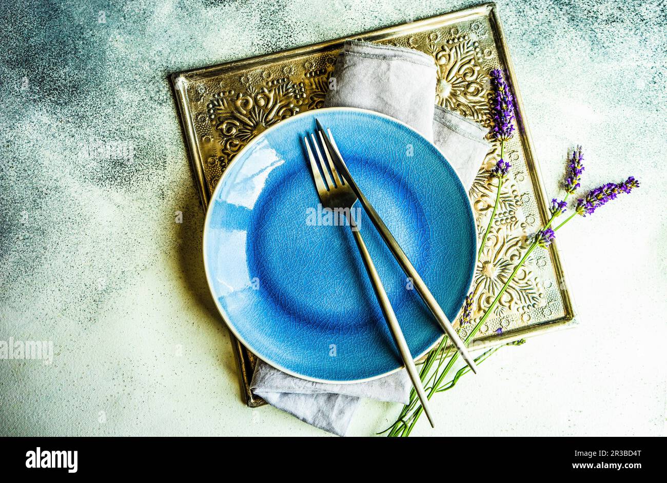 Tavolo estivo con gres minimalistico e posate decorate con fiori freschi di lavanda Foto Stock