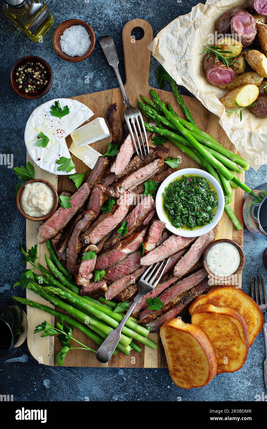 Piatto di bistecca e asparagi con patate e pane tostato Foto Stock