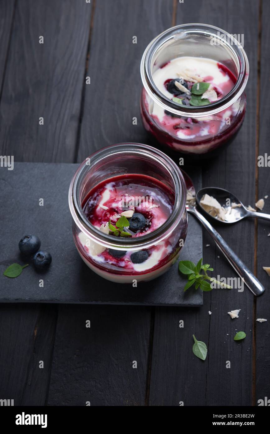 Yogurt di mandorle con composta di mirtillo in un bicchiere Foto Stock