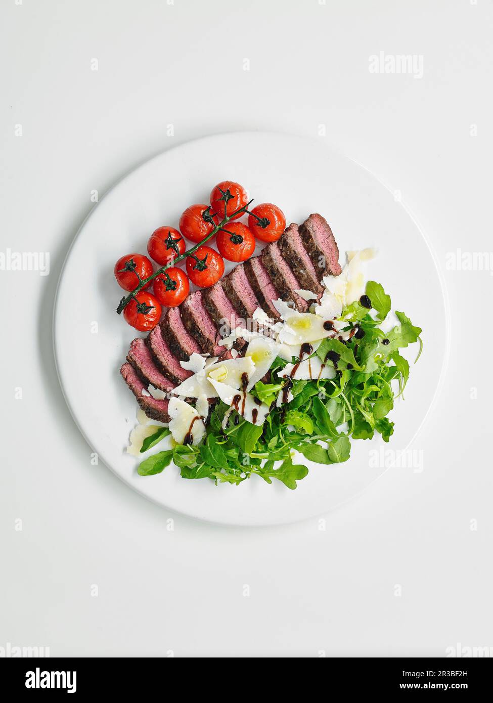 Tagliata di bistecca con pomodori ciliegini, rucola e parmigiano Foto Stock