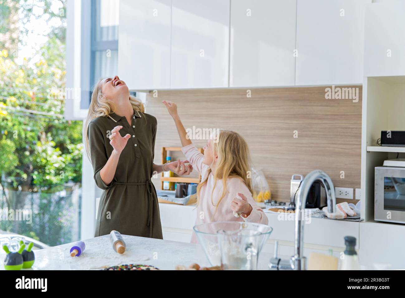 Figlia gioiosa godendo con la madre in cucina a casa Foto Stock