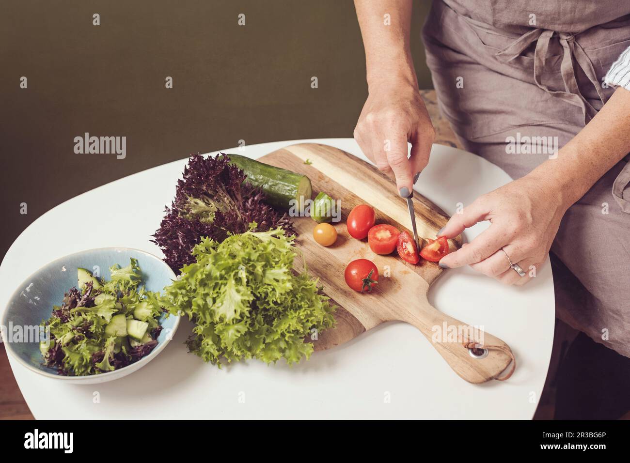 Preparazione dell'insalata - tritare lattuga e pomodori Foto Stock