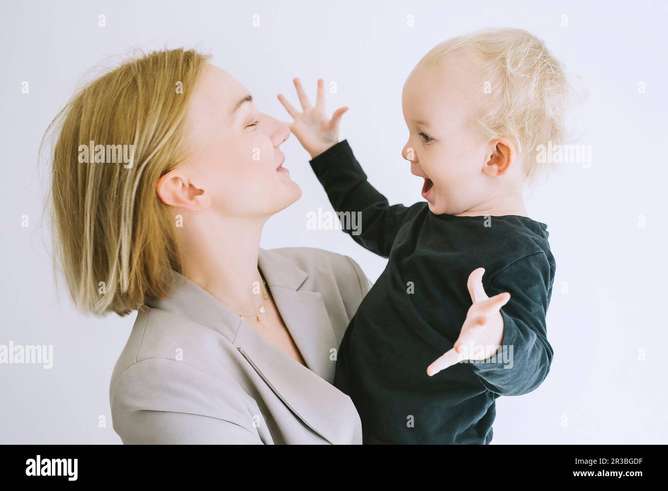 Figlio giocoso con madre su sfondo bianco Foto Stock