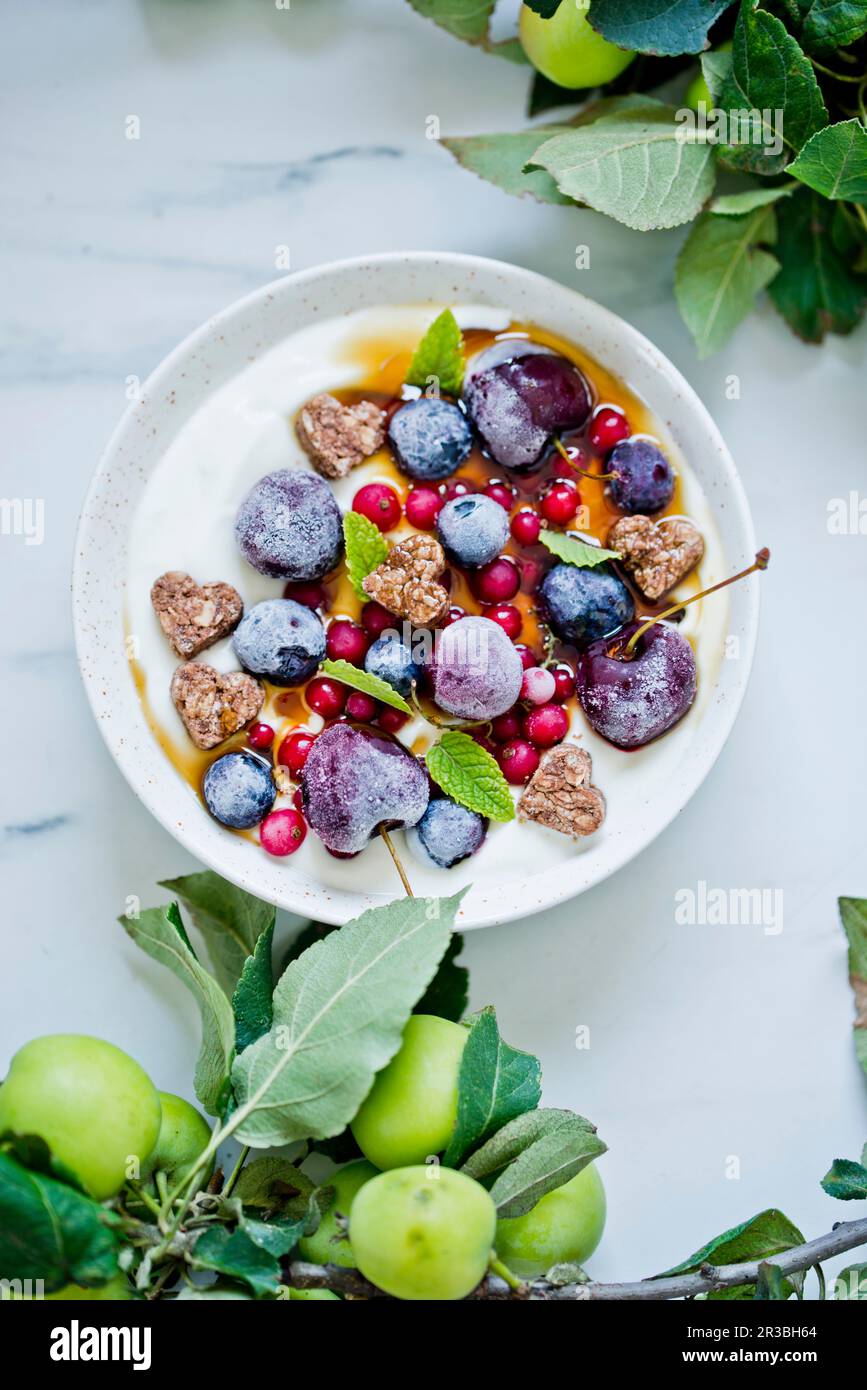 Yogurt con frutta surgelata e cuori di pasticceria Foto Stock