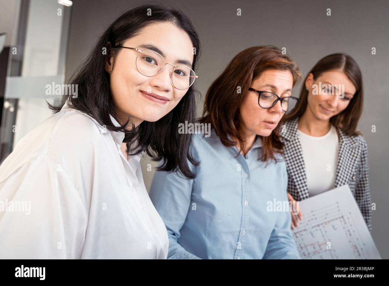 Donna d'affari sorridente che lavora con i colleghi su un progetto architettonico Foto Stock