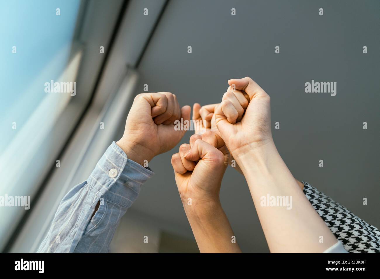 Pugni alzati di uomini d'affari alla finestra Foto Stock