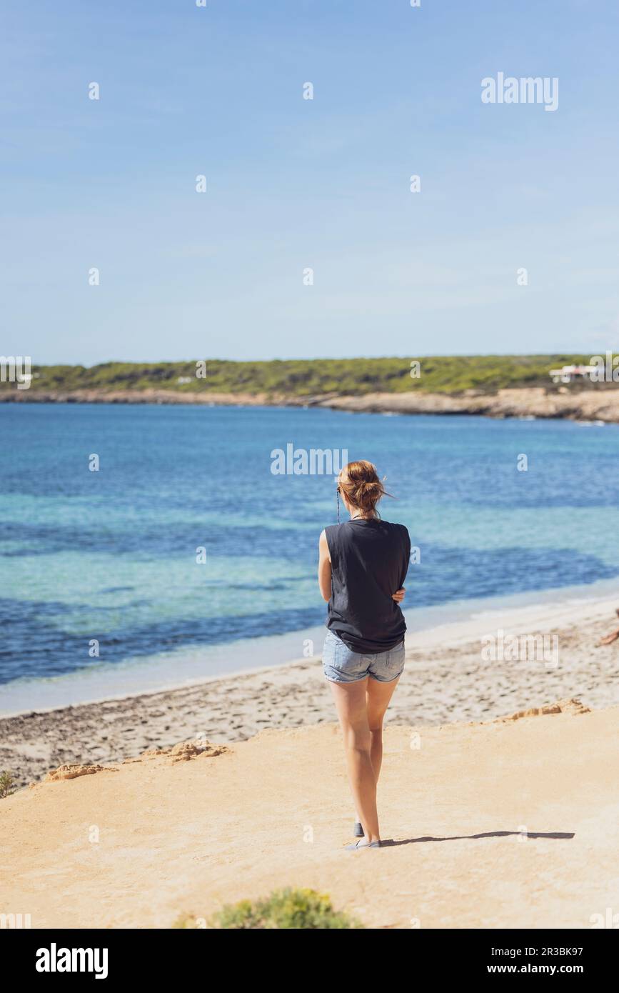 Spagna, Isole Baleari, Formentera, Donna in piedi da sola sulla spiaggia mediterranea Foto Stock