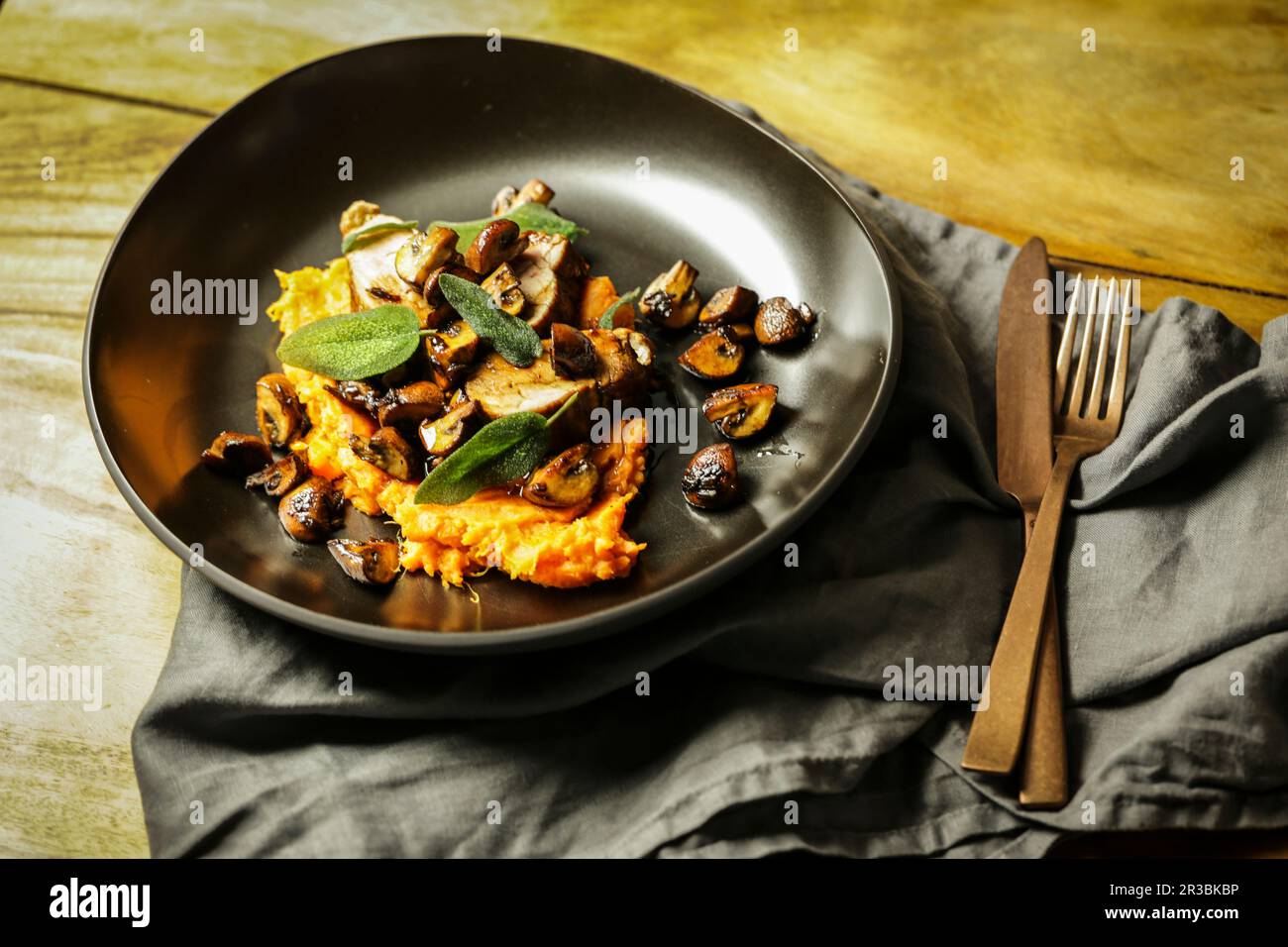 Filetto di maiale con funghi e salvia fritta su un letto di purè di patate dolci Foto Stock