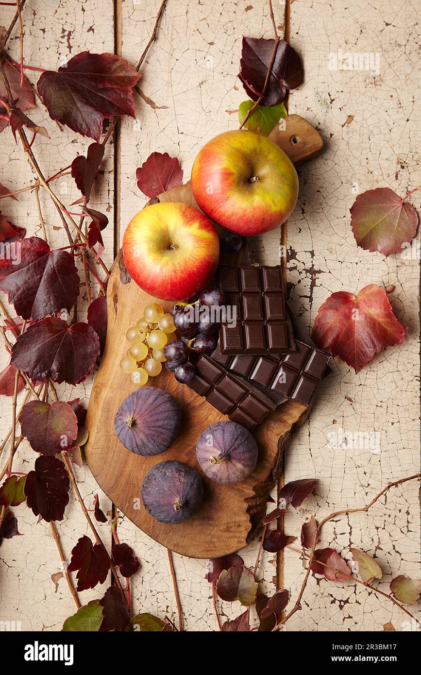 Una composizione autunnale di mele, fichi, uva e cioccolato Foto Stock