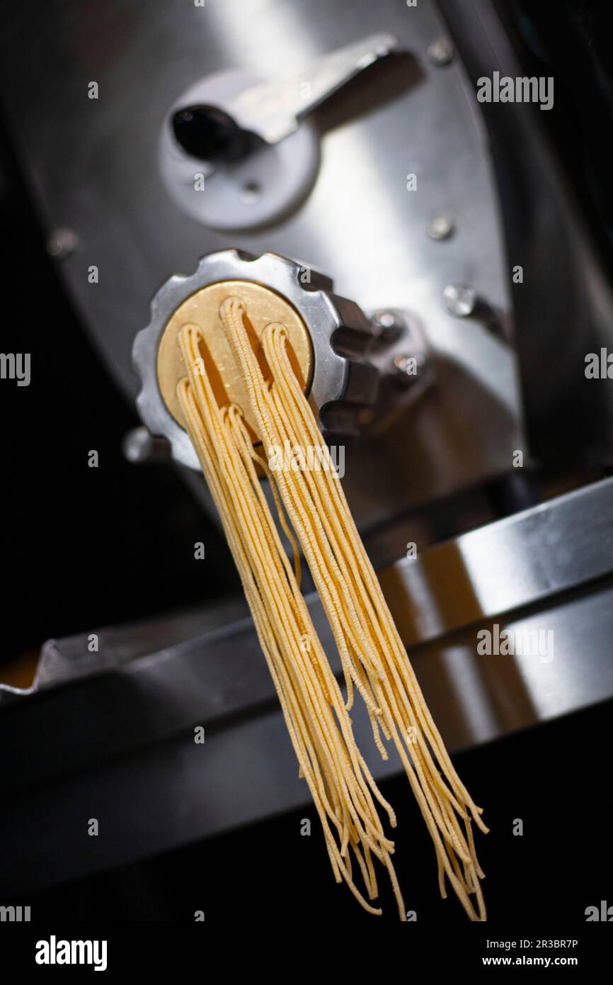 Produzione pasta: Linguine in una macchina per pasta industriale Foto Stock