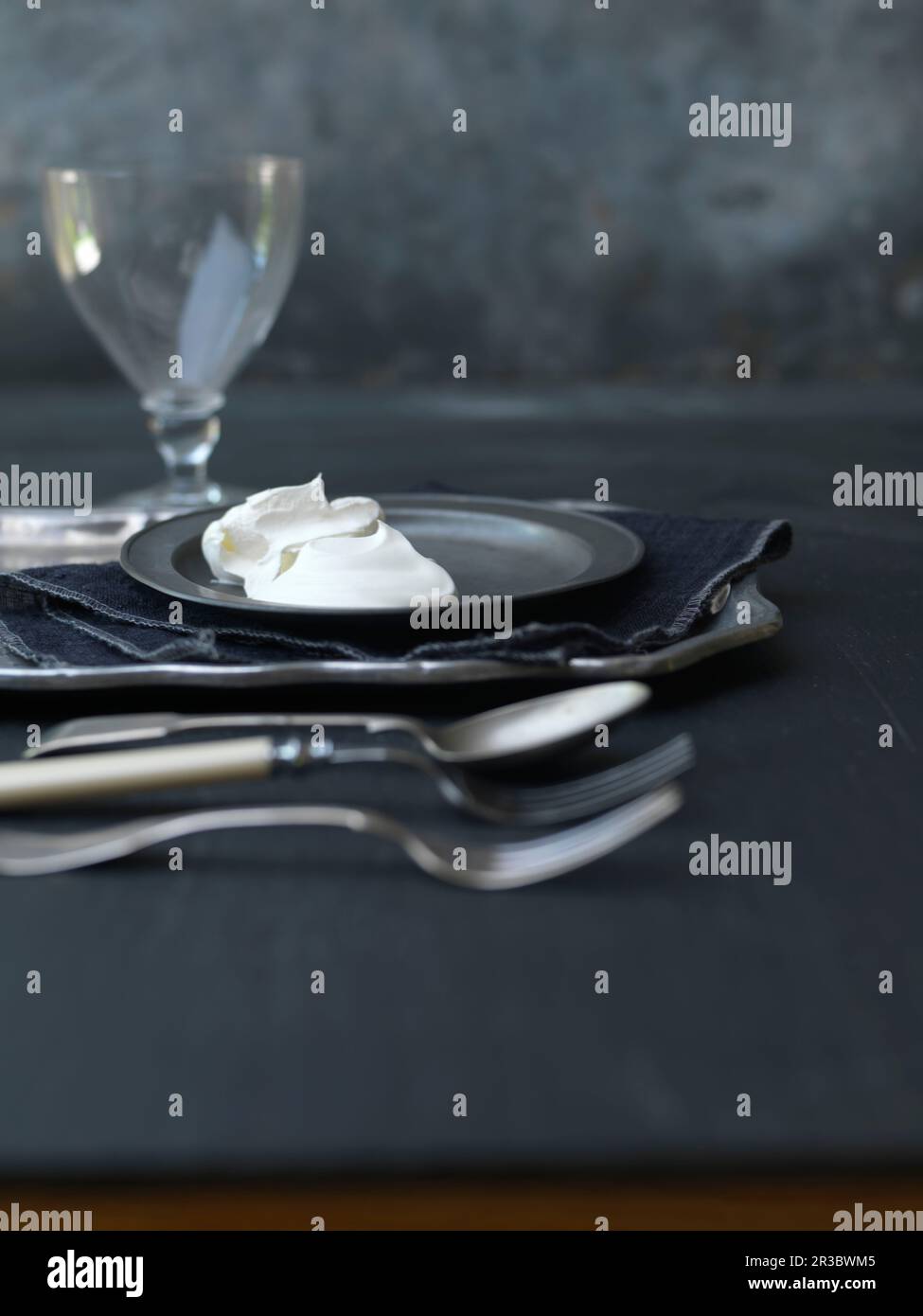 Bambola panna montata su piatto da cucire con posate, tovagliolo e bicchiere di vino Foto Stock