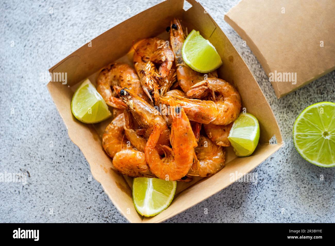 Gamberetti fritti con fettine di lime nella scatola di consegna del fast food Foto Stock