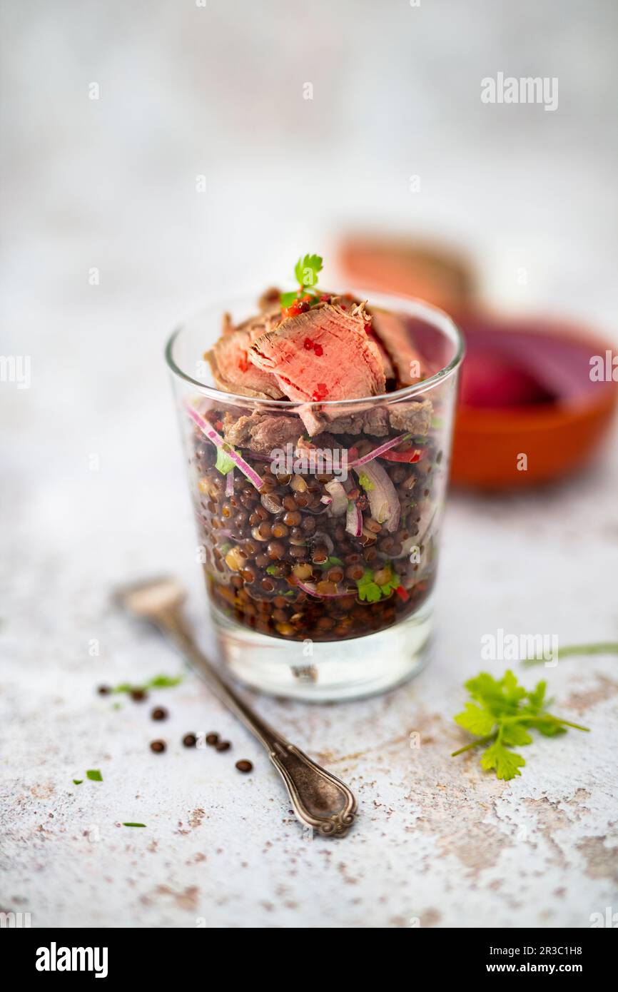 Insalata con lenticchie di beluga e strisce di filetto di manzo in un vasetto Foto Stock