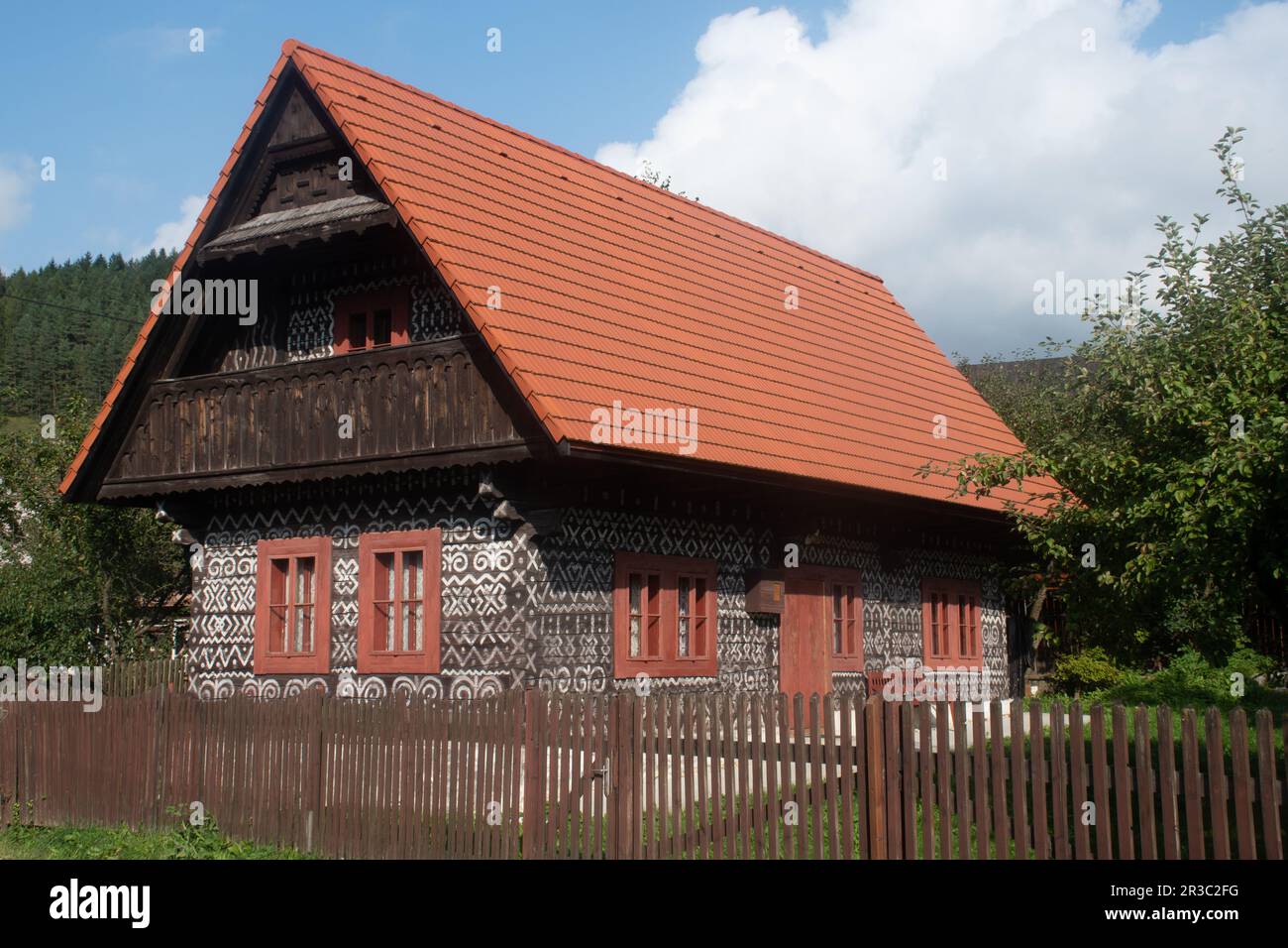 Casa decorata in bianco e nero nel villaggio popolare slovacco di Cicamany con colline a Backgrou Foto Stock