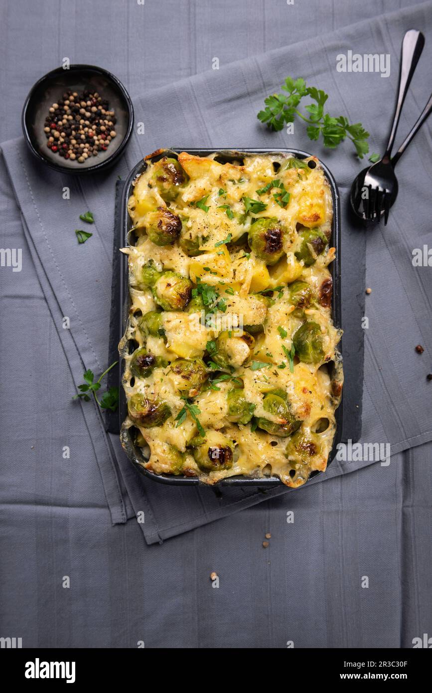 Patate vegane gratinate e germogli di Bruxelles in forno, con formaggio di mandorle Foto Stock