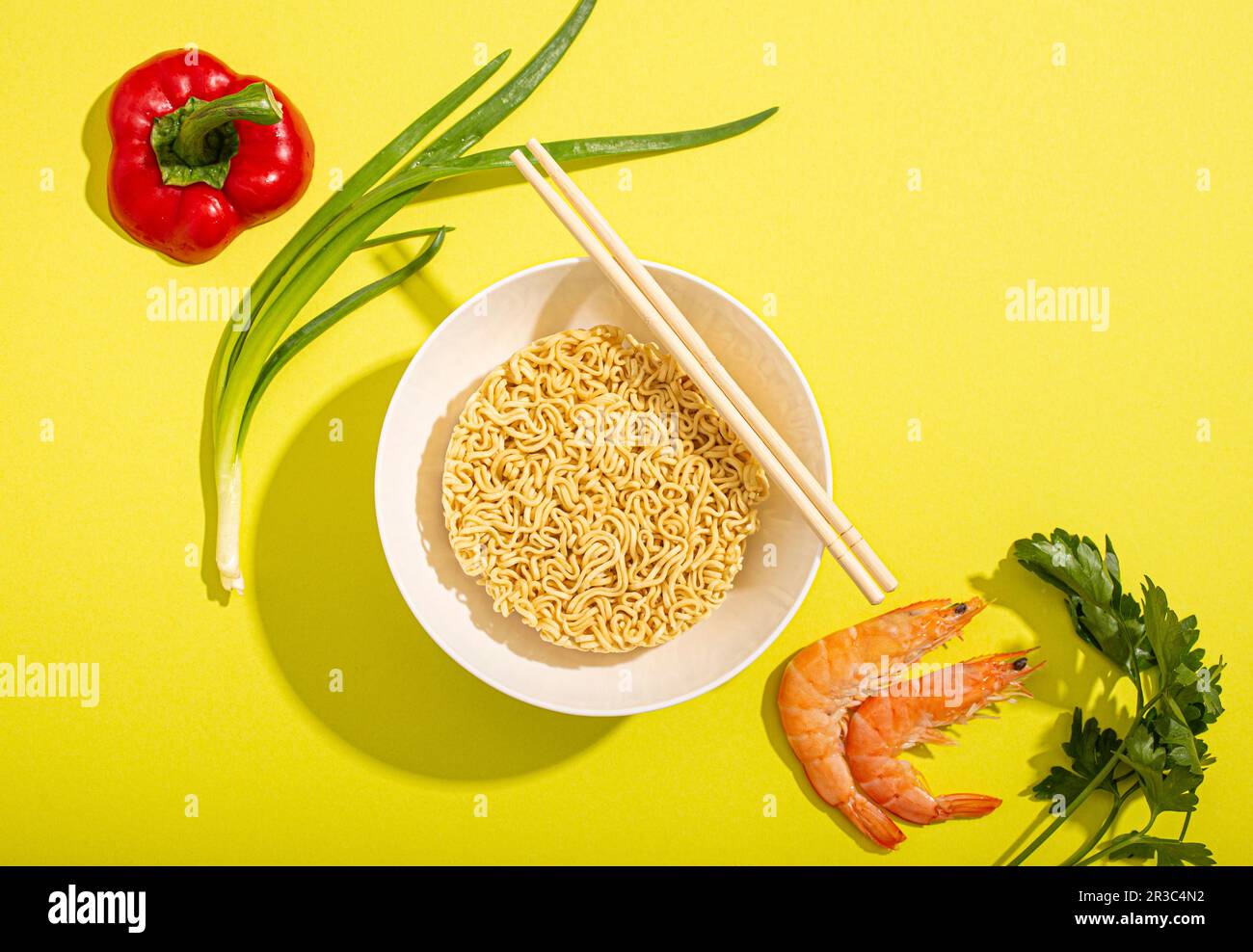 Tagliatelle rapide asiatiche, gamberetti, verdure e cipolla verde su carta gialla brillante Foto Stock
